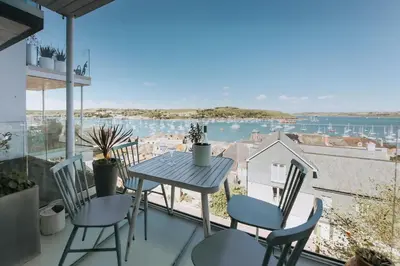 a table and chairs on a balcony with a view of the water at Falmouth View in Falmouth