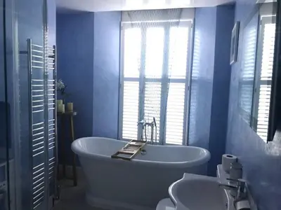 a blue bathroom with a tub and a toilet at Jacob's View in Falmouth