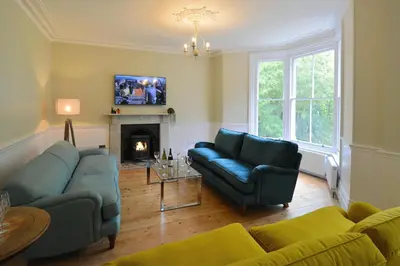 a living room with two blue couches and a fireplace at Rosevean House in St. Agnes