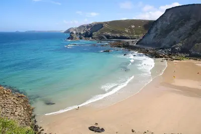 a beach with people swimming in the ocean at Rosevean House in St. Agnes