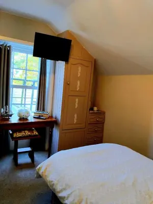 a bedroom with a bed and a dresser and a cabinet at The Countryman Hotel in Camelford
