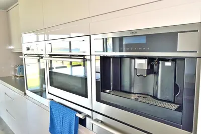 a kitchen with three windows and a blue towel at Ocean View in Perranporth