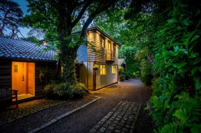 a house with a tree next to a street at Pinetum Garden Cottages in St Austell