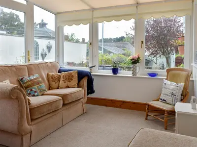 a living room with a couch and some windows at Bay Cottage in Par