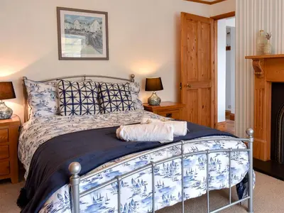 a bedroom with a blue and white bed and a fireplace at Bay Cottage in Par