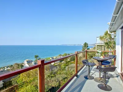a balcony with a table and two chairs and the ocean at Hawks Ridge in Downderry