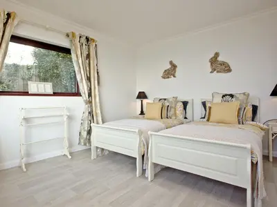 a white bedroom with two beds and a window at Hawks Ridge in Downderry
