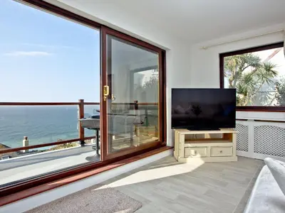 a living room with a flat screen tv and large windows at Hawks Ridge in Downderry