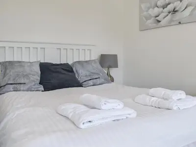 a white bed with three folded towels on it at Caddie - Uk11038 in Carlyon Bay