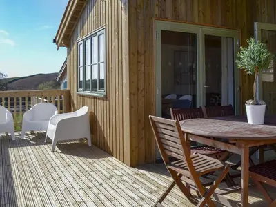 a wooden deck with a wooden table and chairs at Hen Harrier Lodge-Uc3979 in Saint Columb Major