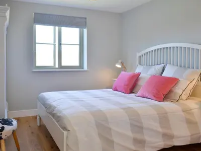 a bedroom with a large bed with pink pillows at Hen Harrier Lodge-Uc3979 in Saint Columb Major