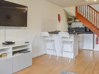 a kitchen with two white bar stools and a flat screen tv at Bunker - Uk11039 in Carlyon Bay