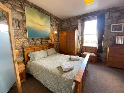 a bedroom with a bed and a stone wall at THE STONES St Ives Apartment Panoramic Harbour Views and Onsite Parking in St Ives