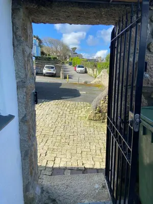 an open door to a cobblestone street with cars parked at THE STONES St Ives Apartment Panoramic Harbour Views and Onsite Parking in St Ives