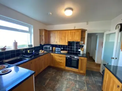 a kitchen with wooden cabinets and a large window at THE STONES St Ives Apartment Panoramic Harbour Views and Onsite Parking in St Ives