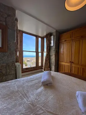 a bedroom with a large bed with a large window at Huers Watch Beautiful Apartment with Panoramic Views over St Ives Bay and private parking in St Ives