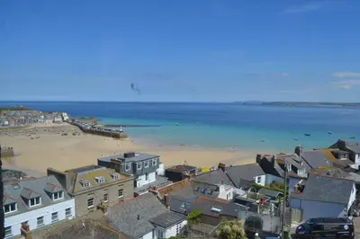 a view of a beach with houses and the ocean at Huers Watch Beautiful Apartment with Panoramic Views over St Ives Bay and private parking in St Ives