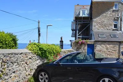 a blue car parked in front of a stone building at Huers Watch Beautiful Apartment with Panoramic Views over St Ives Bay and private parking in St Ives