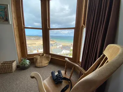 a room with chairs and a window with a view of the ocean at Huers Watch Beautiful Apartment with Panoramic Views over St Ives Bay and private parking in St Ives