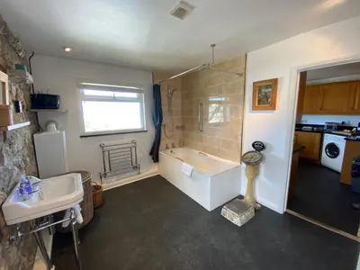 a bathroom with a bath tub and a sink at Huers Watch Beautiful Apartment with Panoramic Views over St Ives Bay and private parking in St Ives
