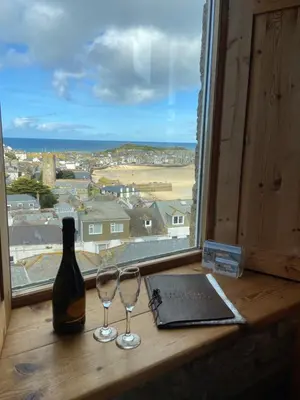 a window with a bottle of wine and two wine glasses at Huers Watch Beautiful Apartment with Panoramic Views over St Ives Bay and private parking in St Ives
