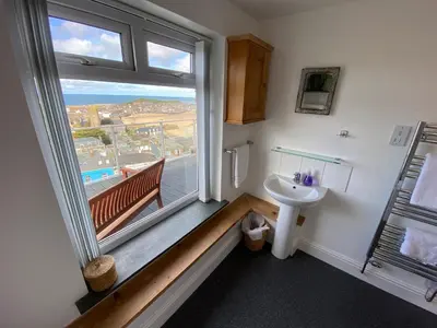 a bathroom with a sink and a large window at THE PENTHOUSE Top Floor Apartment with Bay Views, Large Balcony & Onsite Parking in St Ives