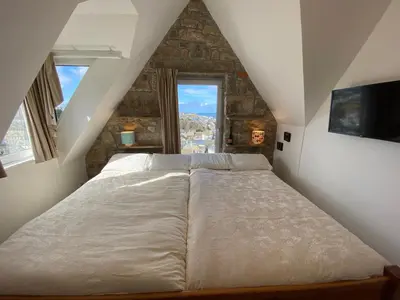 a bedroom with a large bed in a attic at THE PENTHOUSE Top Floor Apartment with Bay Views, Large Balcony & Onsite Parking in St Ives