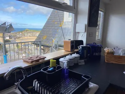a kitchen counter with a sink and a window at THE PENTHOUSE Top Floor Apartment with Bay Views, Large Balcony & Onsite Parking in St Ives