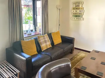 a living room with a leather couch and a table at Trevithick Lodge in Hayle