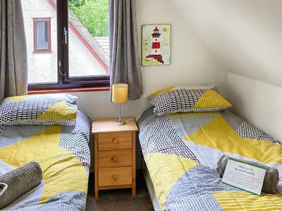 two twin beds in a room with a window at Trevithick Lodge in Hayle