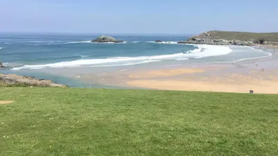 a beach with a green field and the ocean at Great Western Maisonette in Newquay