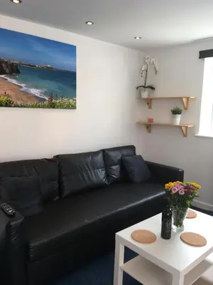 a black leather couch in a living room with a table at Great Western Maisonette in Newquay