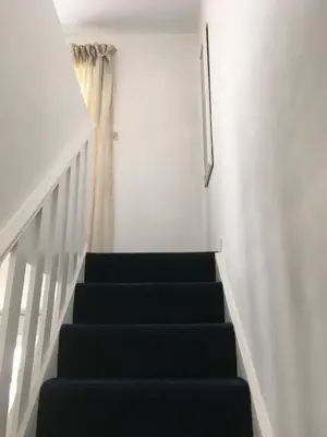 a stairway with black steps and a picture on the wall at Great Western Maisonette in Newquay