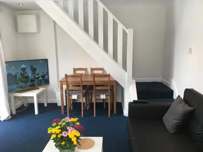 a living room with a couch and a table and a staircase at Great Western Maisonette in Newquay