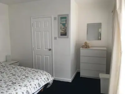 a bedroom with a bed and a dresser and a mirror at Great Western Maisonette in Newquay