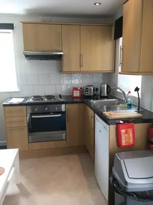 a kitchen with wooden cabinets and a stove top oven at Great Western Maisonette in Newquay