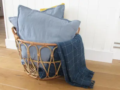 a basket filled with blue pillows on a floor at White Willows in Praa Sands