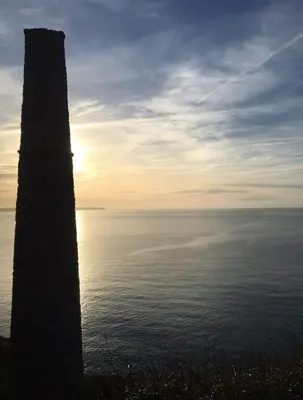 a pole next to the ocean with the sun in the sky at White Willows in Praa Sands