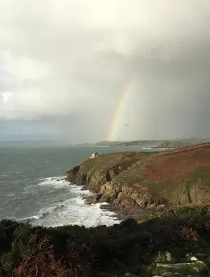 a rainbow in the sky over the ocean at White Willows in Praa Sands