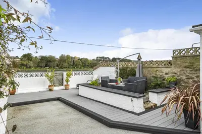 a patio with a table and chairs on top of a building at Waters Edge Holiday Home in Hayle, West Cornwall in Hayle