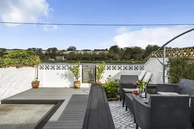 a patio with chairs and tables on a balcony at Waters Edge Holiday Home in Hayle, West Cornwall in Hayle