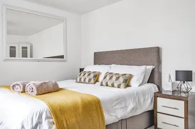 a white bedroom with two beds and a mirror at Waters Edge Holiday Home in Hayle, West Cornwall in Hayle