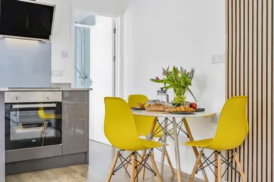 a kitchen with a table with yellow chairs at Waters Edge Holiday Home in Hayle, West Cornwall in Hayle