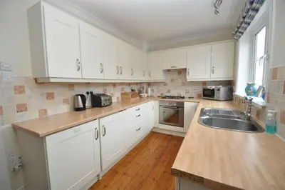 a kitchen with white cabinets and a sink at The Old Quayside House in Falmouth