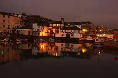 a group of houses and boats on the water at night at The Old Quayside House in Falmouth