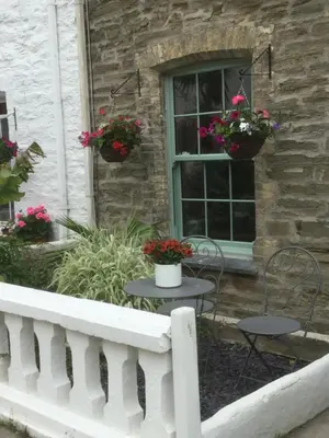 a porch with two tables and chairs and flowers at Bambu Cottage in Newquay
