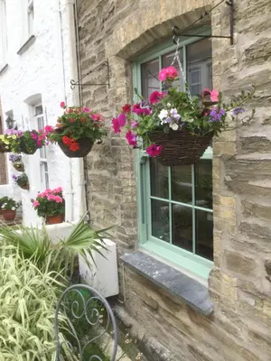 a window with flower baskets on the side of a building at Bambu Cottage in Newquay