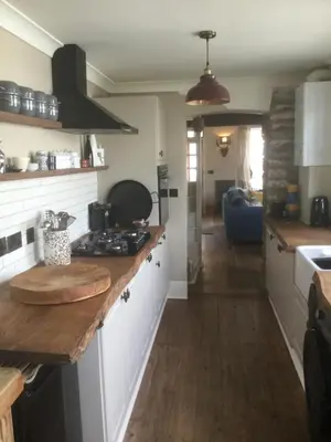 a kitchen with white cabinets and a wooden counter top at Bambu Cottage in Newquay