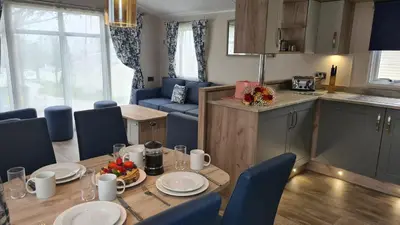 a kitchen and dining room with a table and blue chairs at Hendra Holiday Park in Newquay