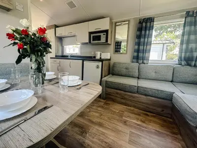 a kitchen and living room with a table and flowers at Hendra Holiday Park in Newquay